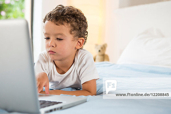 Boy using laptop on bed