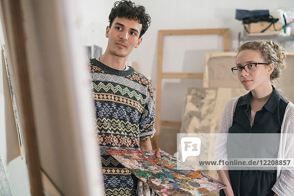Kunde beobachtet männlichen Künstler beim Malen von Leinwand im Ateliertisch des Künstlers