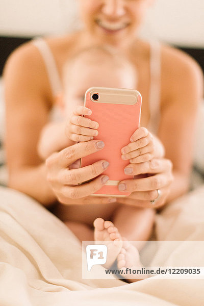 Baby girl and mother's hands gripping smartphone  close up