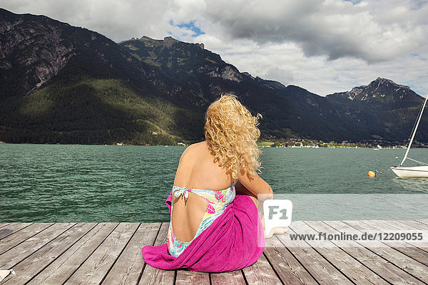 Rückansicht einer auf dem Pier sitzenden Frau  die den Blick abwendet  Innsbruck  Tirol  Österreich  Europa