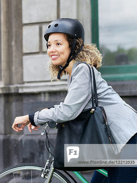 Mittlere erwachsene Frau  die auf dem Fahrrad sitzt und einen Schutzhelm trägt
