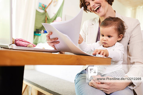 Mother looking at paperwork with baby girl sitting on her lap