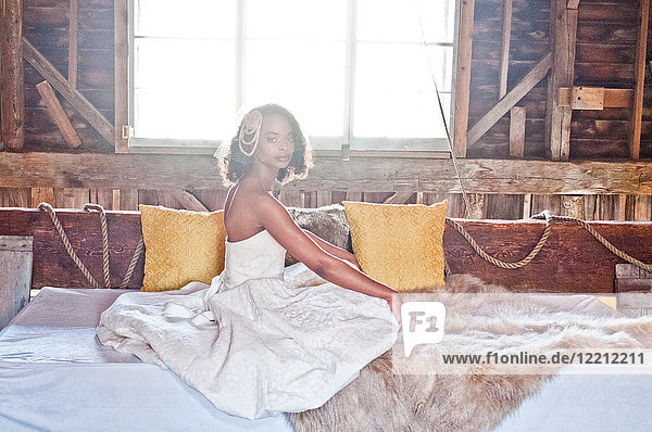 Portrait of bride wearing wedding dress  sitting in barn
