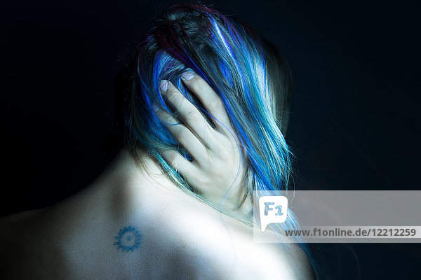 Rückansicht der Frau mit der Hand im blauen Haar  unauffällige Studioaufnahme