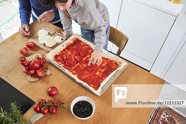 Grandmother and grandson making pizza in kitchen  elevated view