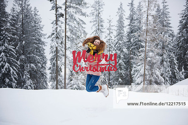 Junge Frau springt mit fröhlichen Weihnachtsworten im Schnee
