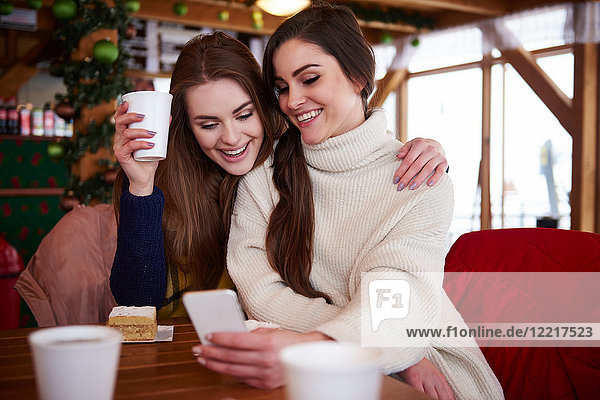 Young women smiling over text message on mobile phone