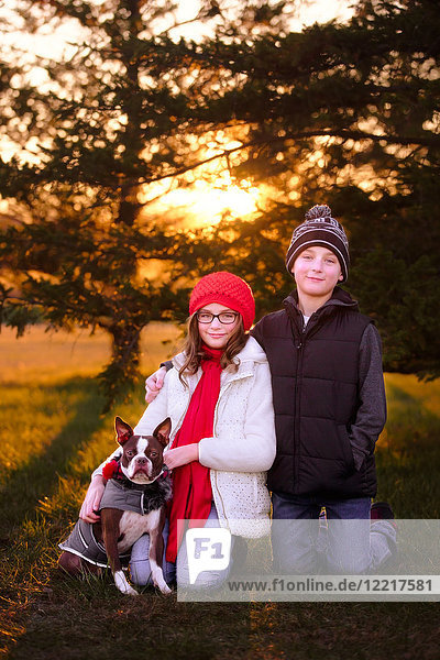 Porträt eines Mädchens und eines Jungen  mit Boston-Terrier-Hund  im Freien