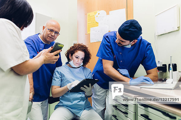 Zahnärzte in der Zahnarztpraxis schauen auf digitales Tablet  Laptop und Smartphone