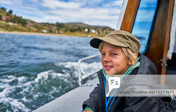 Boy looking out from motor boat at sea  Puno  Peru