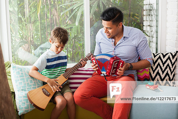 Gitarre spielender Junge mit Musiklehrer auf Fenstersitz