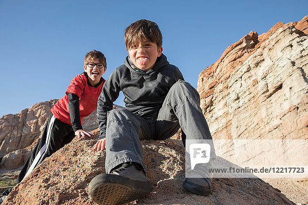 Portrait of boys sitting on rock looking at camera  sticking out tongue  Lone Pine  California  USA