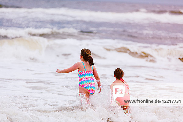 Zwei Mädchen spielen in Meereswellen  Rückansicht  Dauphin Island  Alabama  USA