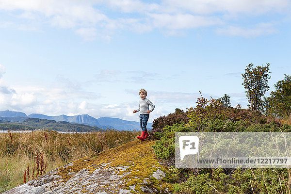 Boy playing on rock near fjord  Aure  More og Romsdal  Norway