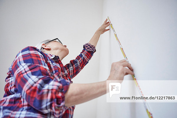 Woman measuring white wall