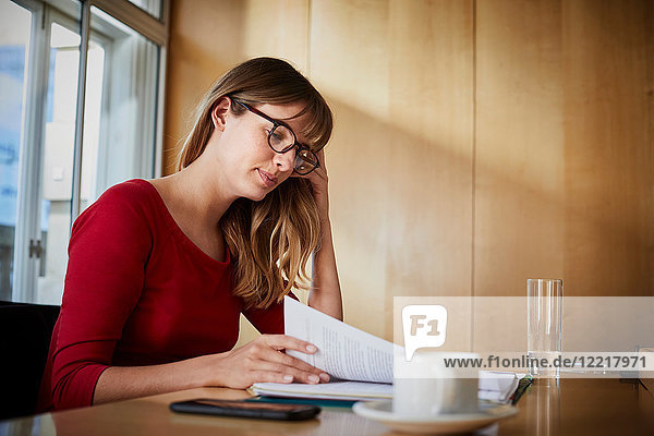 Geschäftsfrau liest Papierkram am Vorstandstisch