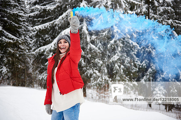 Young woman with smoke flare in snow