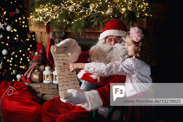 Junges Mädchen zu Besuch beim Weihnachtsmann  zeigt auf Liste