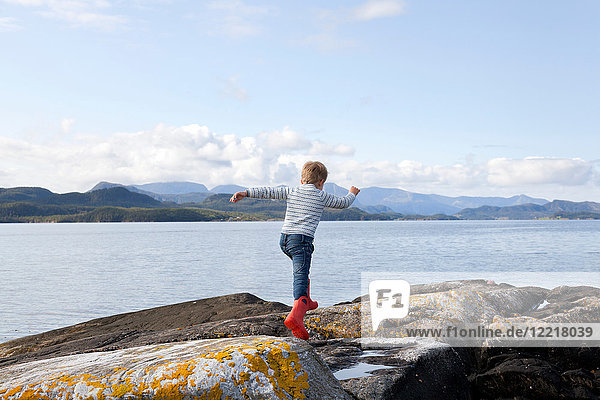 Junge springt über Felsen am Fjord  Aure  More og Romsdal  Norwegen