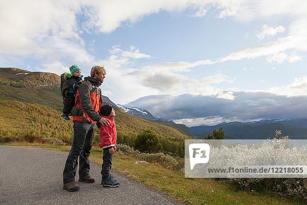 Mann mit Söhnen mit Blick auf die Berglandschaft  Jotunheimen-Nationalpark  Lom  Oppland  Norwegen