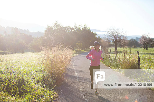 Young woman running along rural road