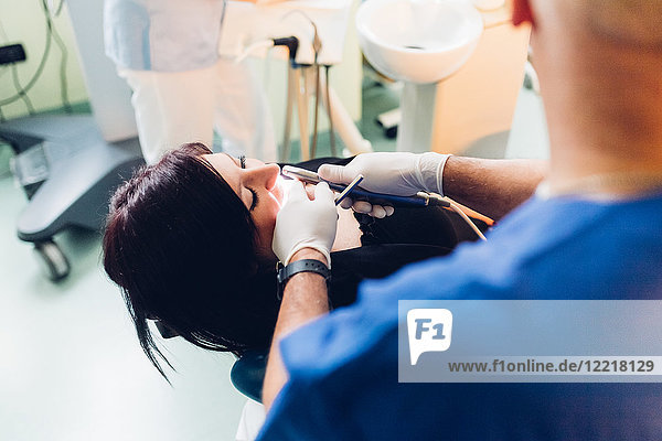 Zahnarzt führt zahnärztlichen Eingriff an weiblicher Patientin durch