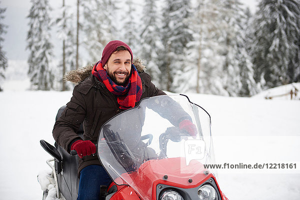 Young man riding snowmobile in winter