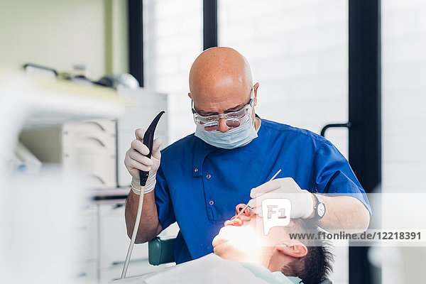 Zahnarzt führt zahnärztlichen Eingriff an männlichem Patienten durch