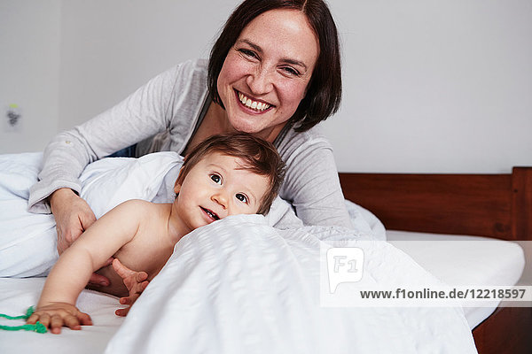 Mother and baby daughter relaxing on bed  smiling