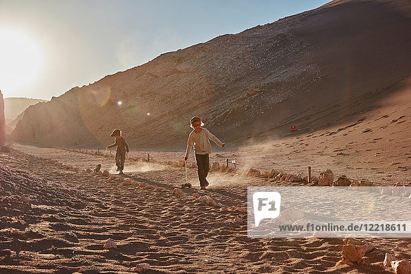 Junge und sein Bruder ziehen Spielzeuglastwagen auf Wüstenpfad  Atacama  Chile