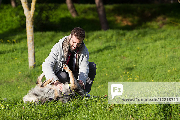 Mann spielt mit Hund im Parkgras