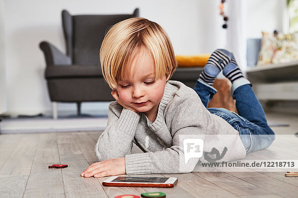 Young boy lying on floor  using smartphone  looking at screen