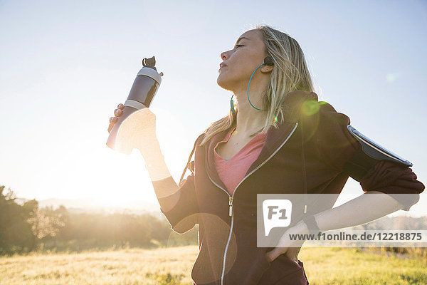 Junge Frau  die sich im Freien bewegt und eine Wasserflasche hält