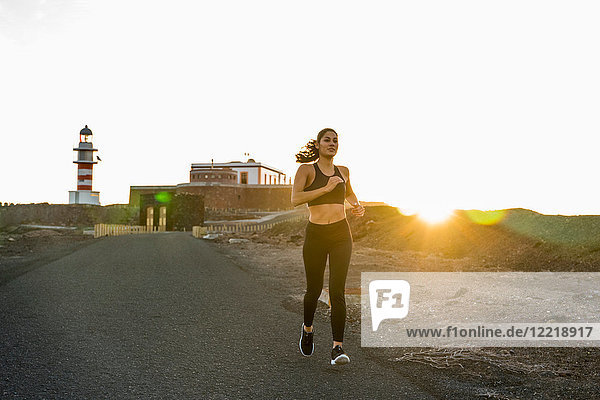Junge Läuferin läuft bei Sonnenuntergang die Landstraße hinunter  Las Palmas  Kanarische Inseln  Spanien