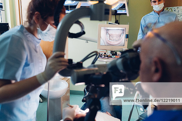 Zahnarzt und Zahnarzthelferin führen Verfahren am Patienten durch