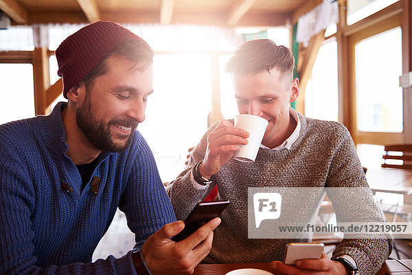 Young men smiling over text message on mobile phones