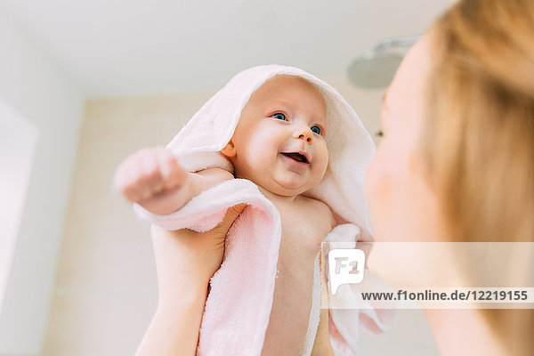 Mother holding baby daughter wrapped in towel