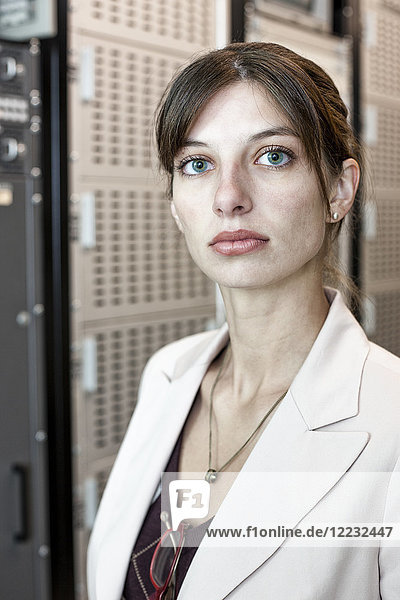 Porträt einer Technikerin die in einem großen Computer-Serverraum arbeitet.