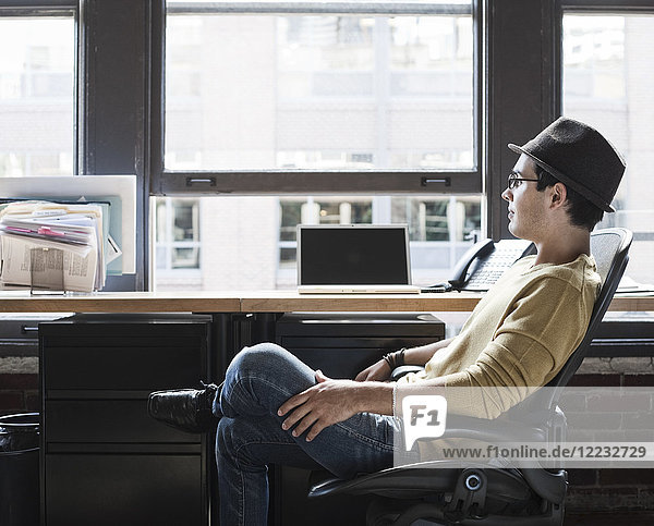 Hispanic male at his office workstation in a creative office.
