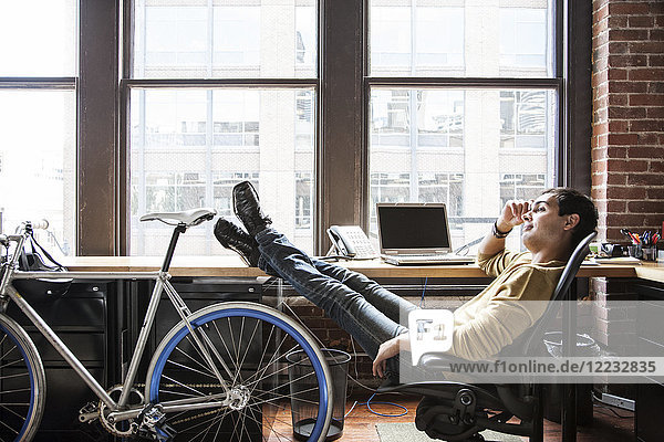 Ein spanischer Mann an seinem Büroarbeitsplatz mit einem Fahrrad.
