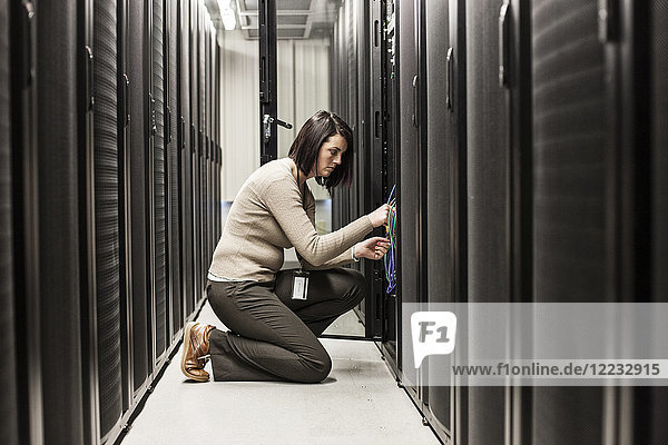 Caucasian woman technician working on computer servers in a server farm.