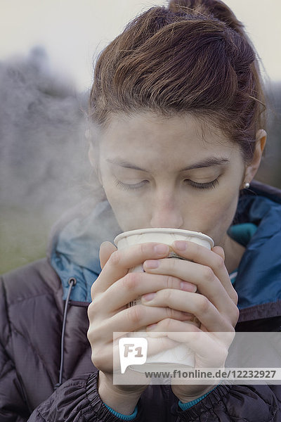 Kaukasische Frau  die an einem Wintertag eine heiße Tasse Kaffee trinkt.