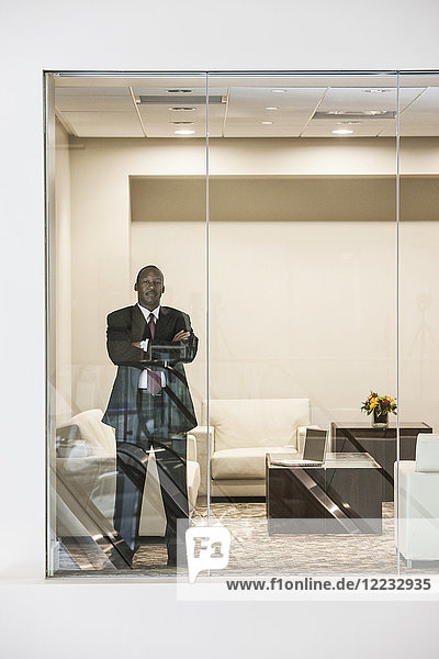 Black businessman standing in conference room window.
