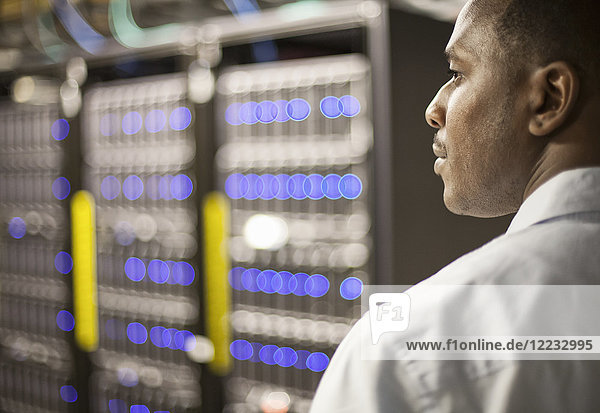 Schwarzer Techniker  der Diagnosetests auf Computerservern in einer Serverfarm durchführt.