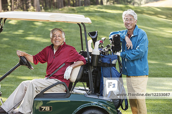 Two senior male golfing buddies and their golf cart and clubs.