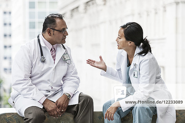 Ein spanischer Mann und eine asiatische Ärztin beraten sich über einen Fall in einem Krankenhaus.