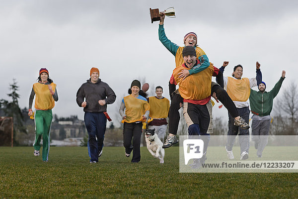 Teammitglieder  die im Winter bei einer Sportveranstaltung im Freien einen Sieg und eine Trophäe feiern.