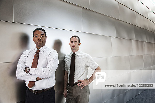 Two businessmen standing in an office corridor.