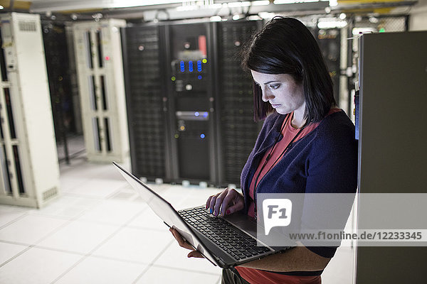 Caucasian woman technician in a large computer server farm.