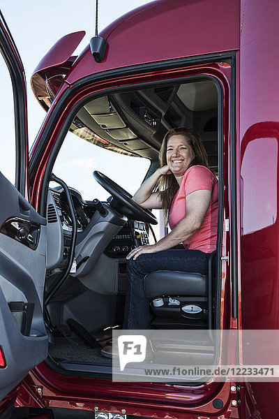 Porträt einer kaukasischen Fahrerin und ihres Lastwagens.